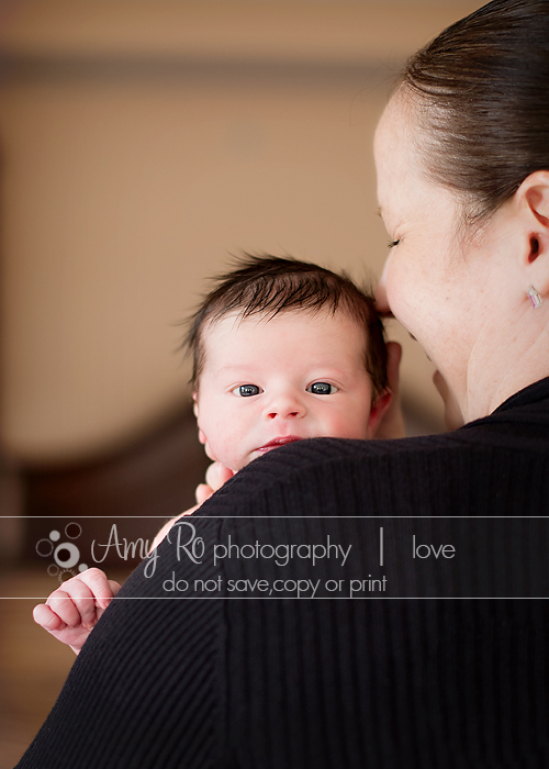 Newborn photo of baby looking over mom's shoulder