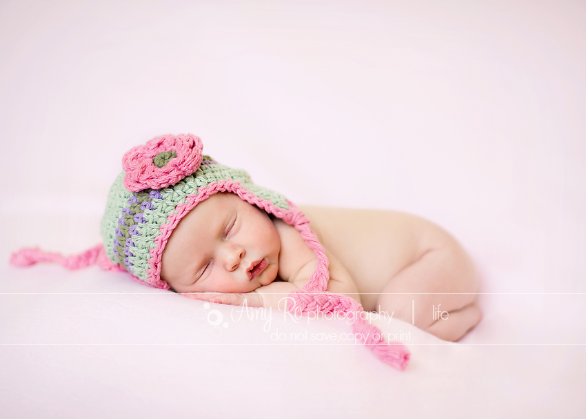 Beautiful newborn baby girl on pink blanket with pink and green hat