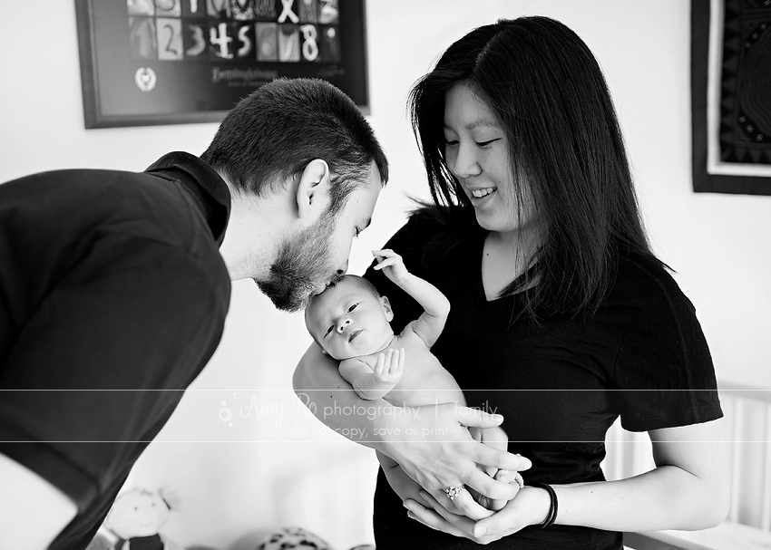 Beautiful image of dad kissing newborn baby while mom holds her