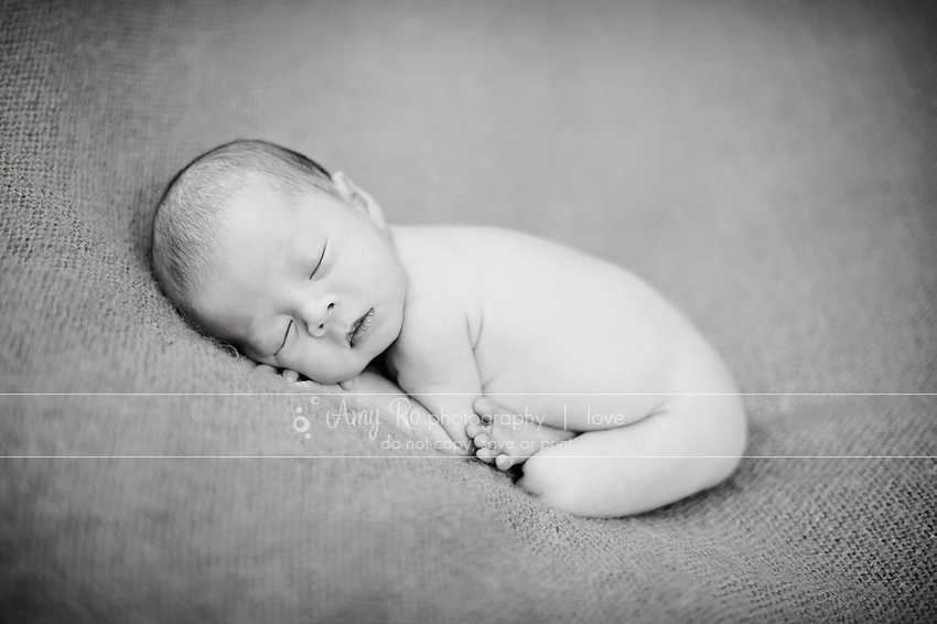 Black and white image of newborn curled up sleeping