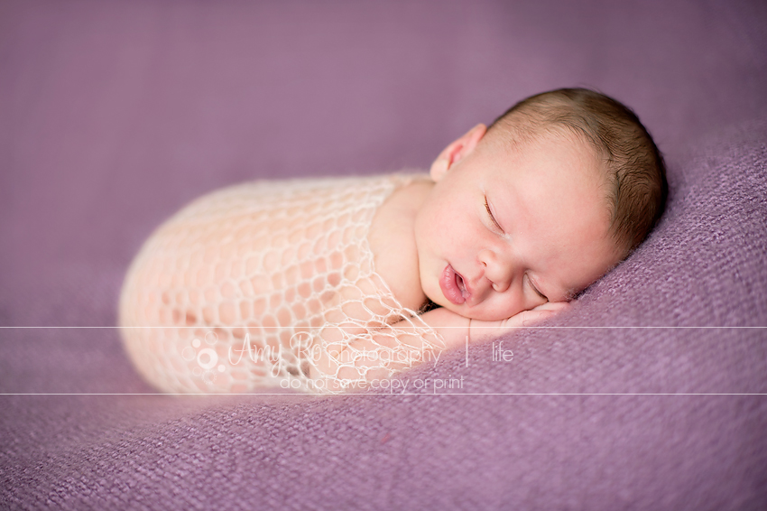 Newborn in wrap newborn on purple blanket