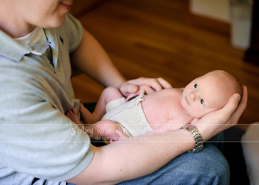 Awake newborn being held by dad