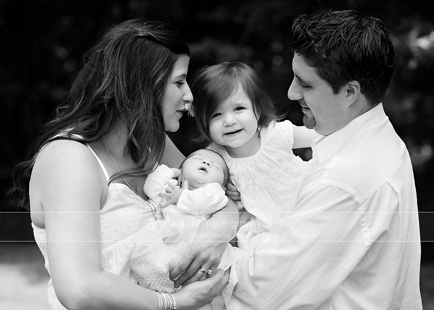 Black and white family image with newborn, siblings