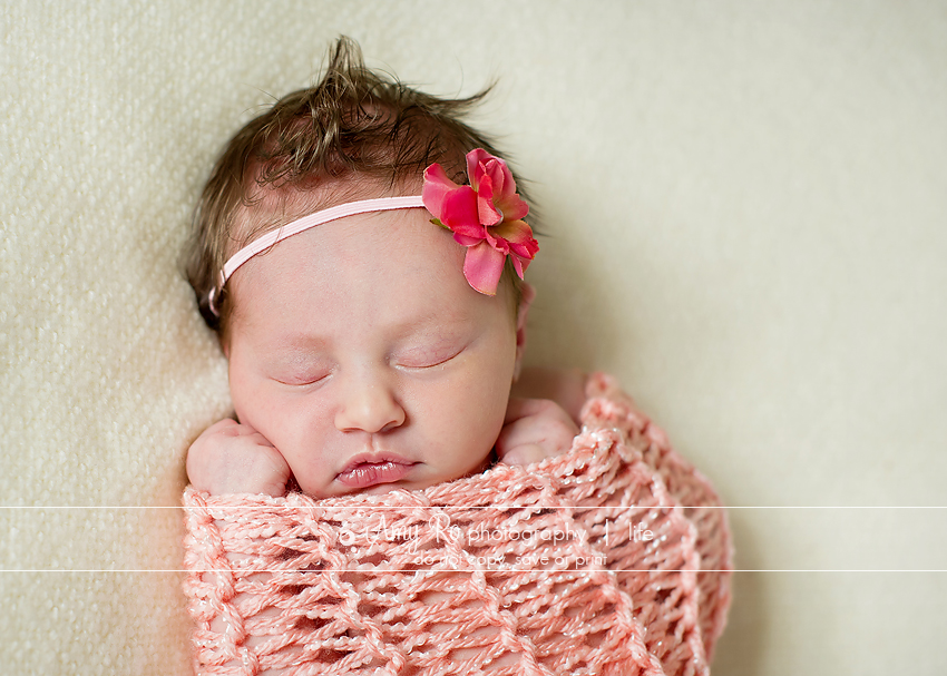 Swaddled baby girl in pink wrap with headband,