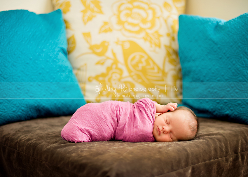 Newborn girl on couch with yellow, purple and teal