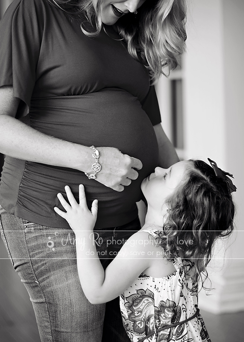 Black and white image of daughter kissing mom's belly