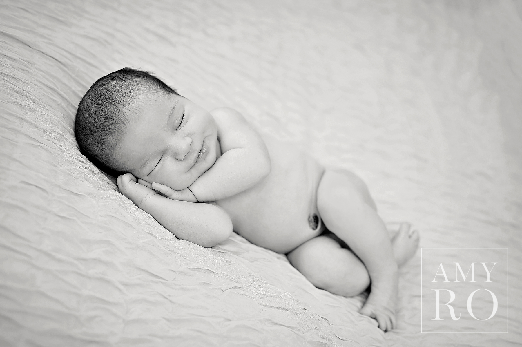 Black and white image of sleeping newborn smiling taken during newborn photography session in Rhode Island