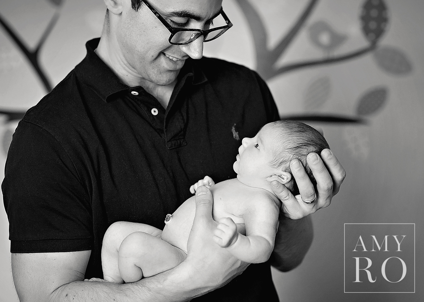 Black and white image of dad looking at newborn baby daughter in nursery shot during  lifestyle newborn on-location session