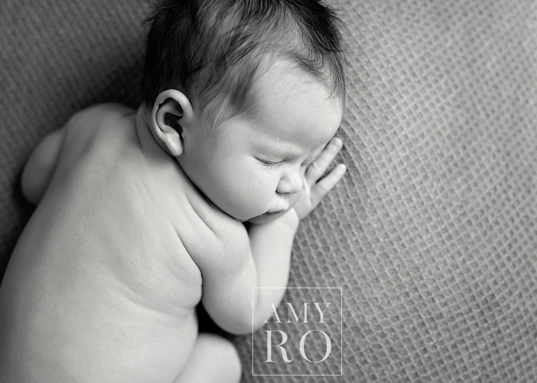 Black and white image of newborn curled on their side during a newborn lifestyle session in Massachusetts