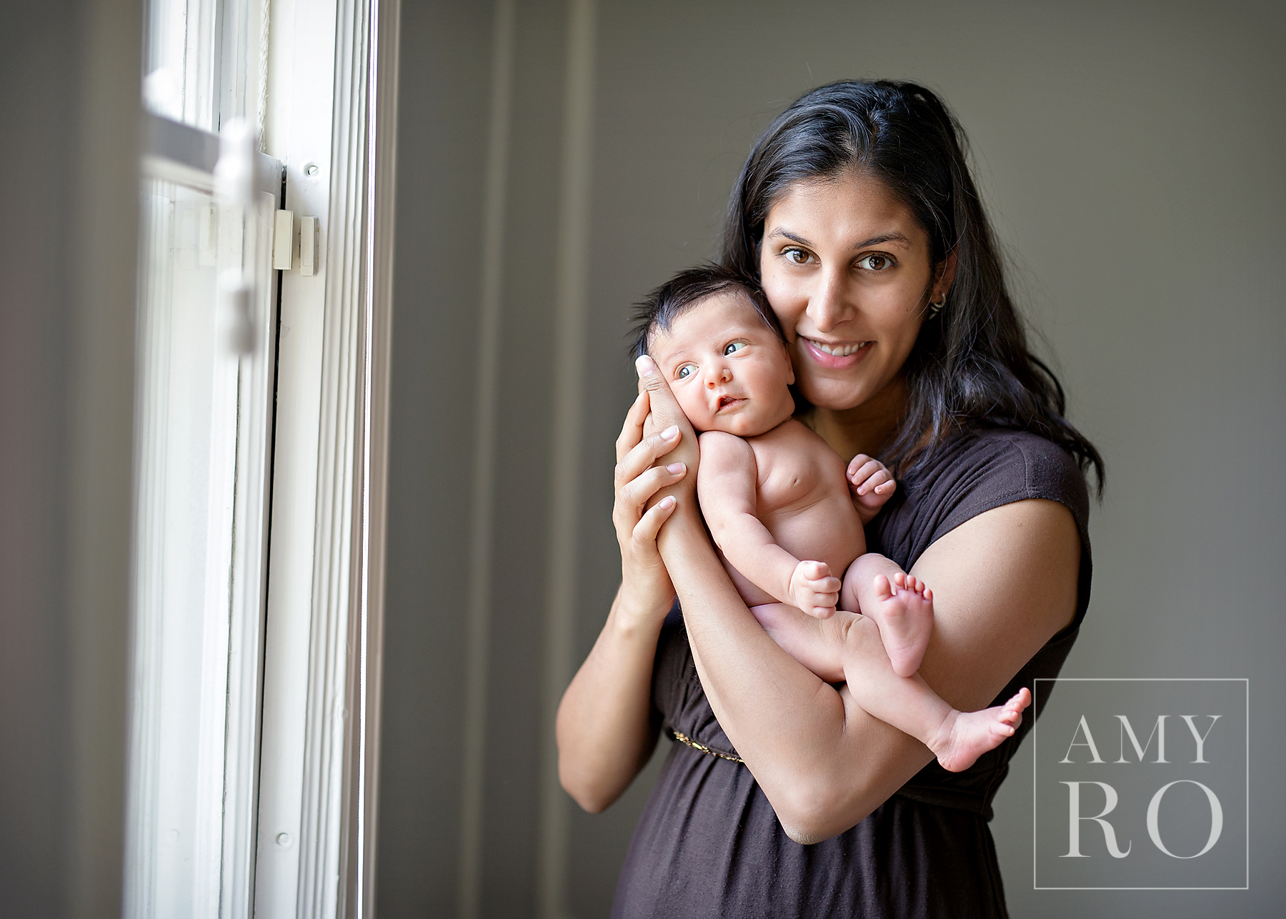 Beautiful image of mother with her newborn daughter in window light during a newborn lifestyle session