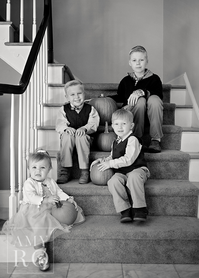 Image of four siblings on stairs with pumpkins during in home session in Rhode Island
