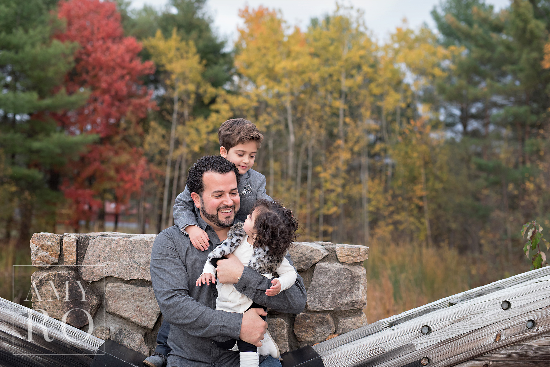 Dad with his two kids in front of fall foliage during a family photography session in Rhode Island