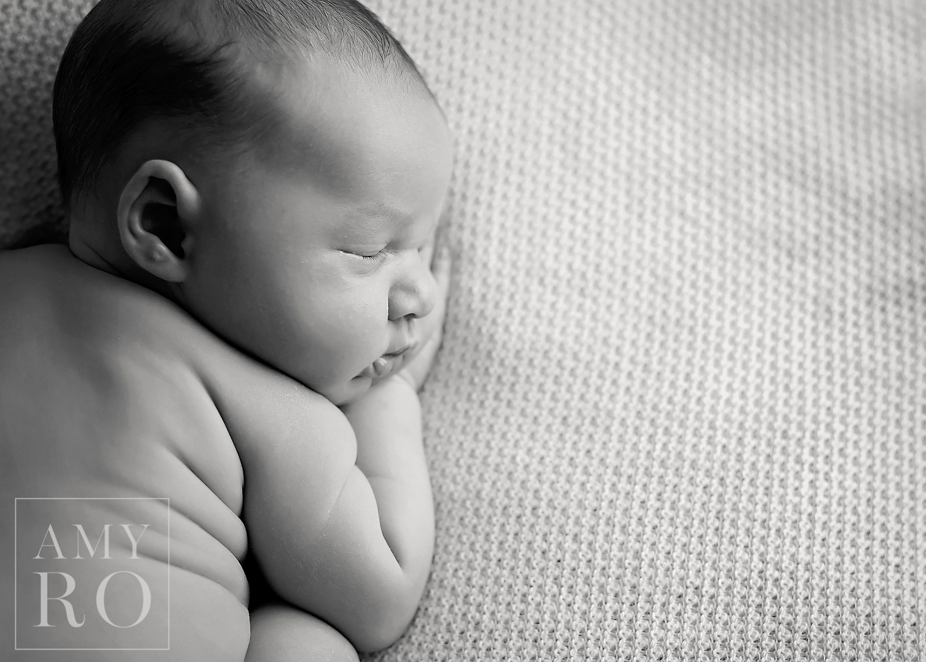 Black and white profile image of newborn baby sleeping on white blanket during newborn session in Rhode Island