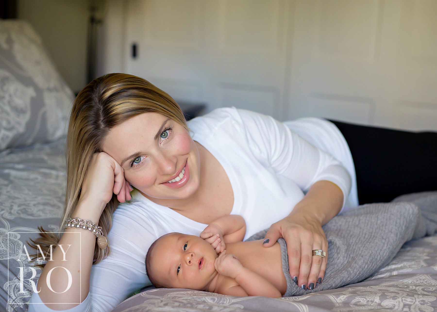 Mom with newborn boy on the bed snuggled up during a lifestyle newborn session in Rhode Island
