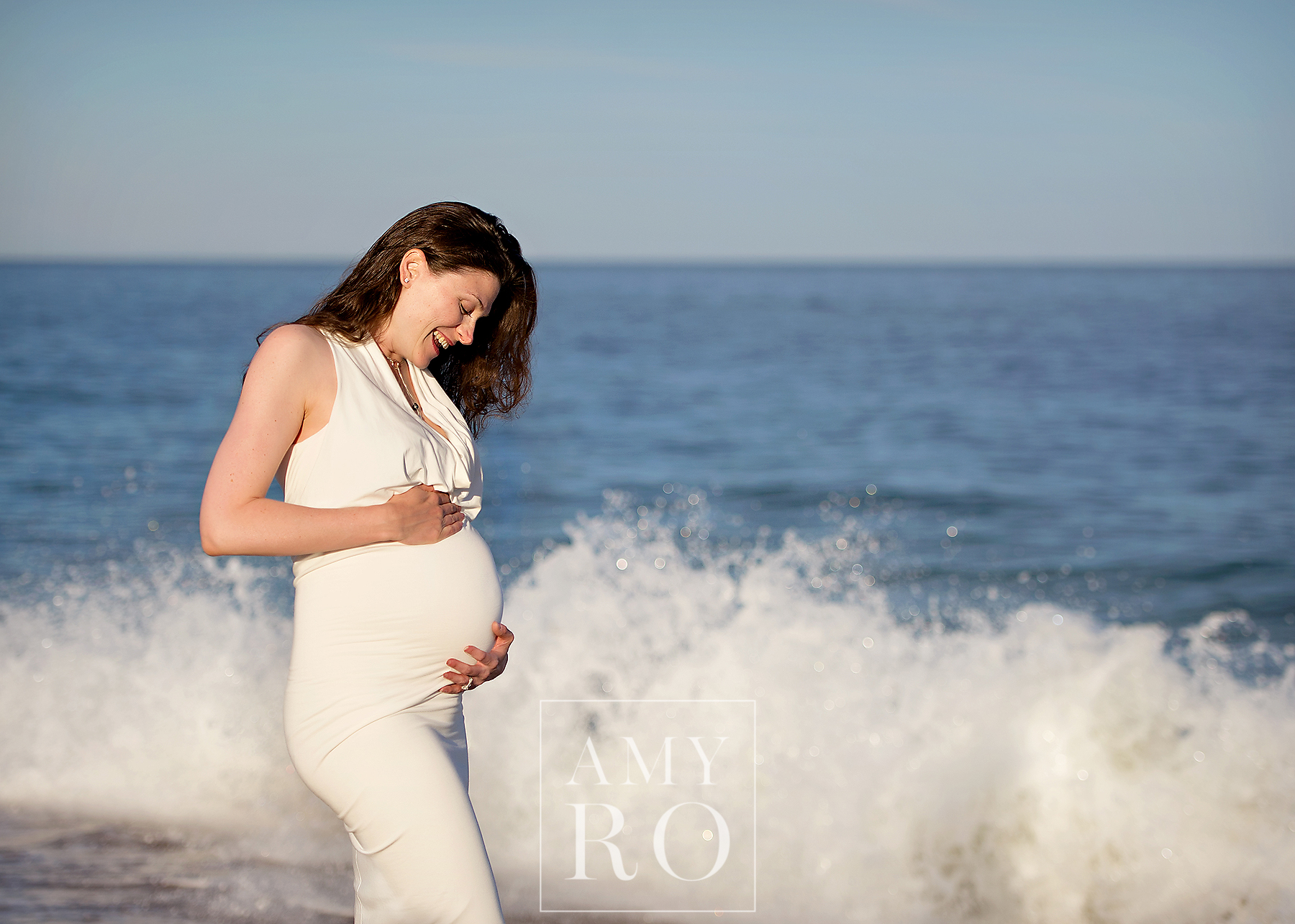 Seaside maternity image with the wave crashing in the background taken at the Weekapaug Inn during a summer maternity session in Rhode Island
