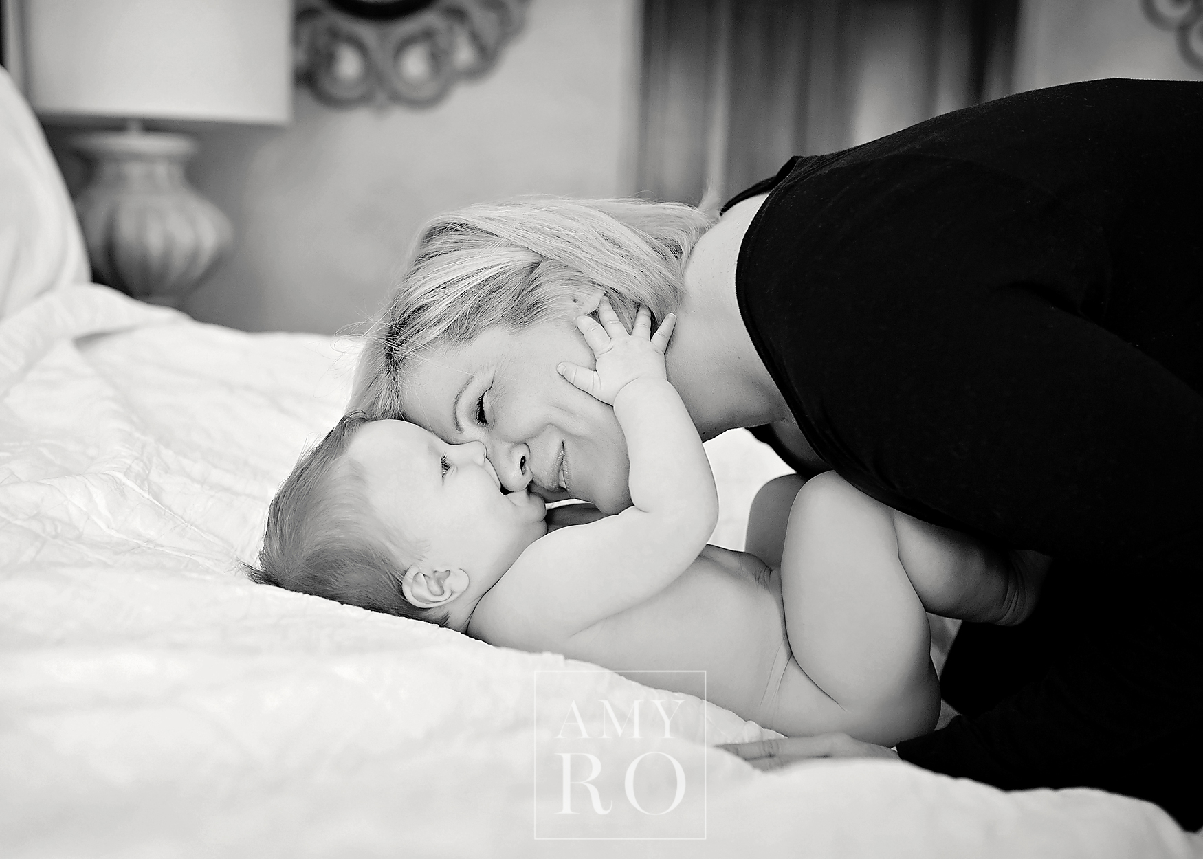 Black and white image of mom and baby snuggling on bed