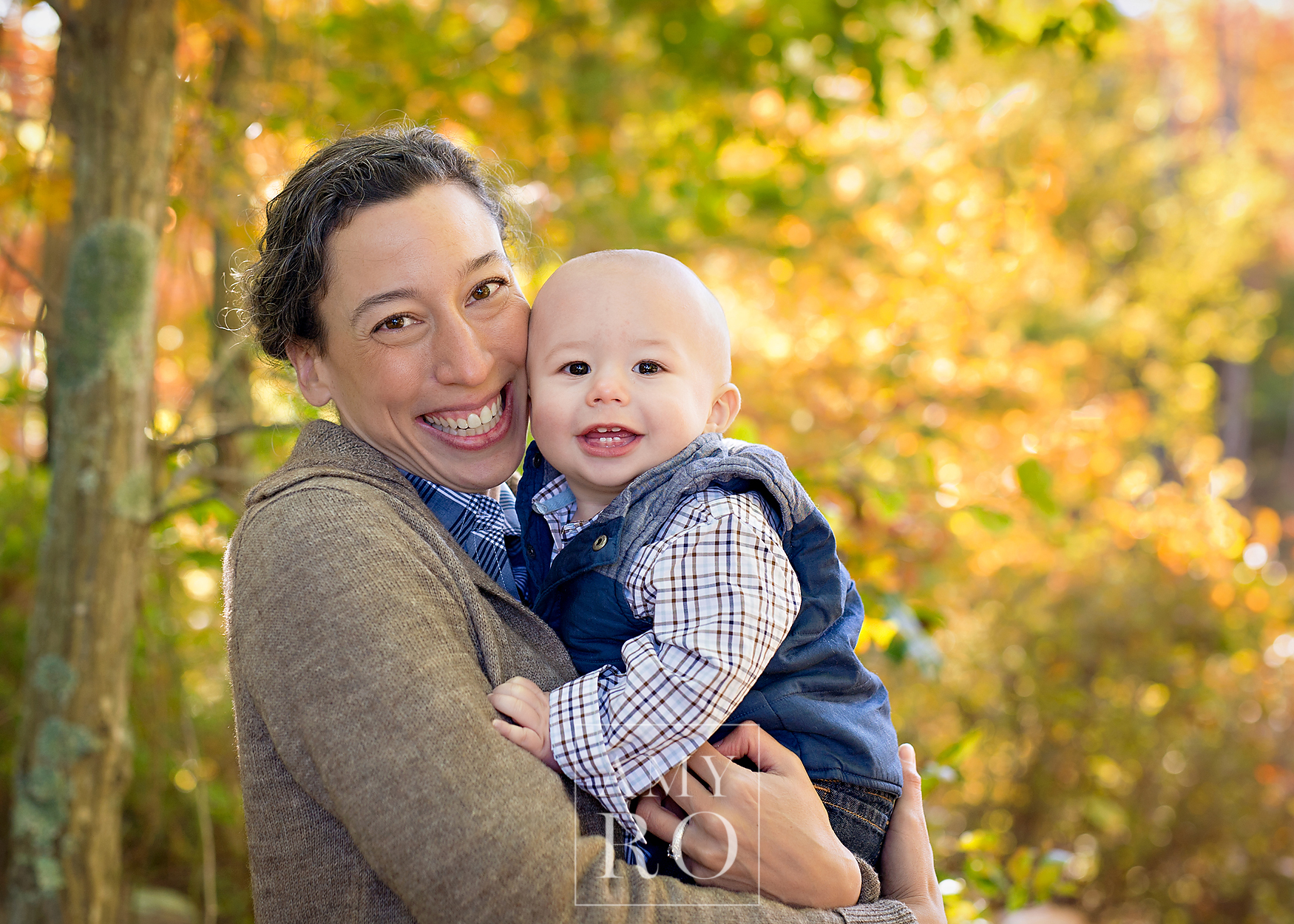 Color fall image of mom holding baby son in the woods during a session in Wrentham Massachusetts
