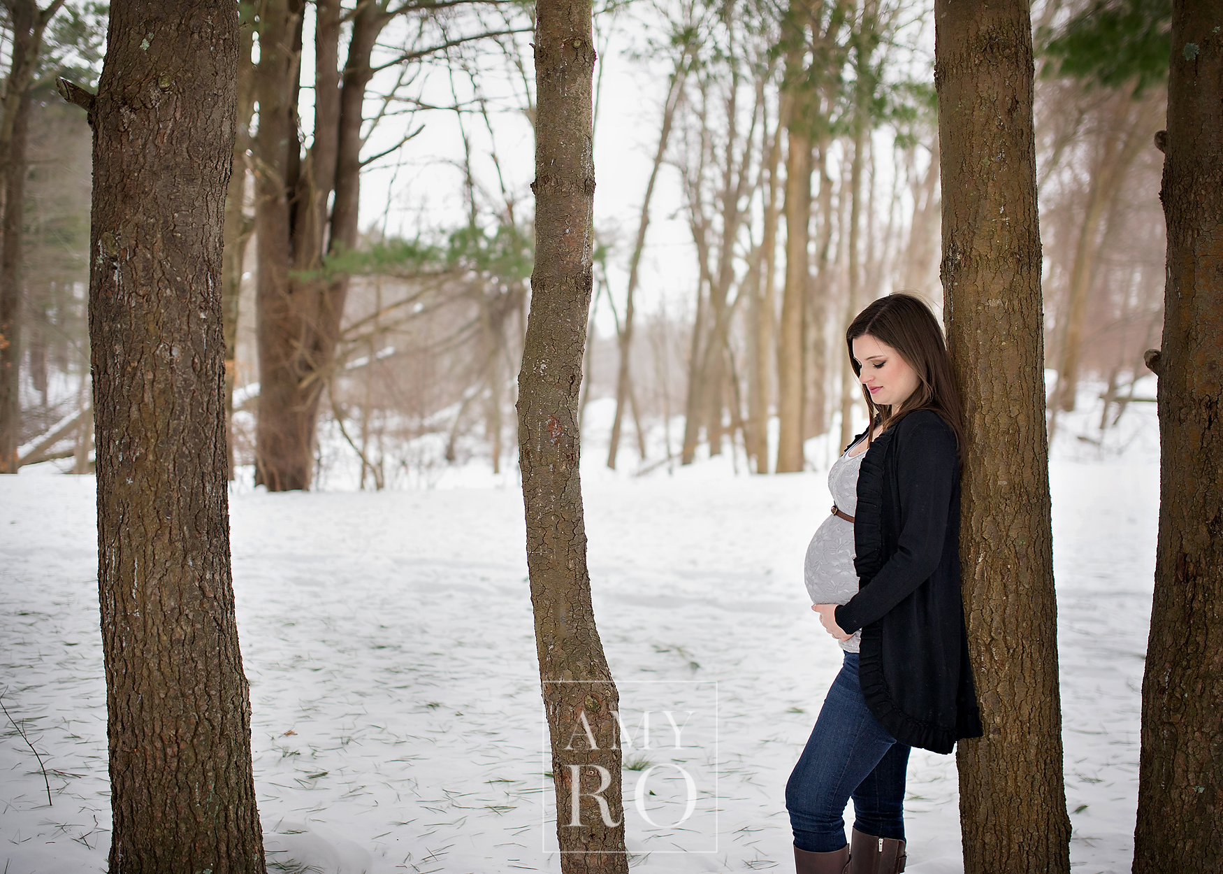 Maternity session in the snow leaning against a tree