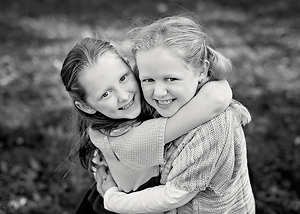 Black and white image of sisters hugging shot durting a family session in Rhode Island