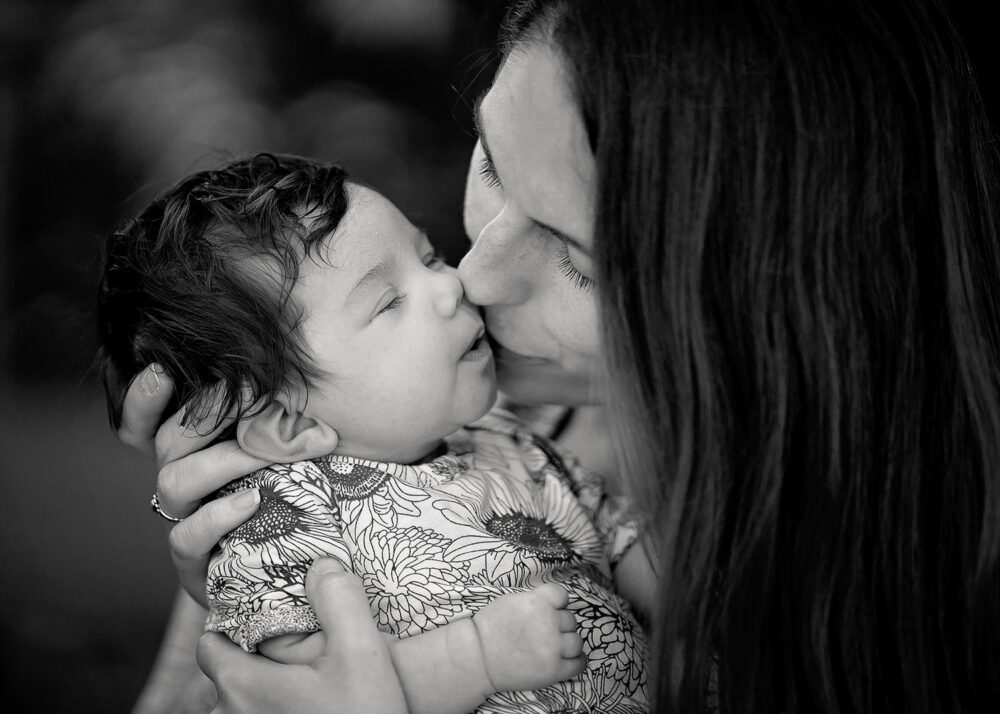 Mom kissing baby during outdoor newborn photos in east providence rhode island