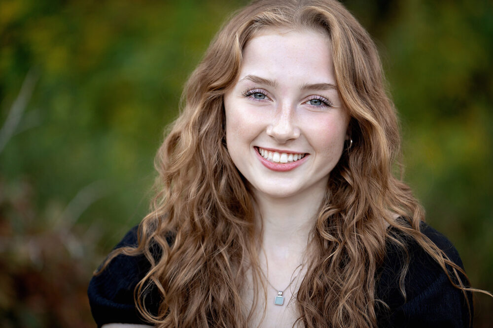 Redhead senior with freckles smiling during photos at Rhode Island beach