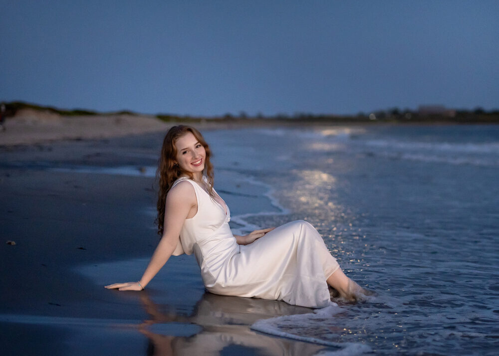 Girl sitting in the water in the moonlight during senior photos at Second beach Rhode Island
