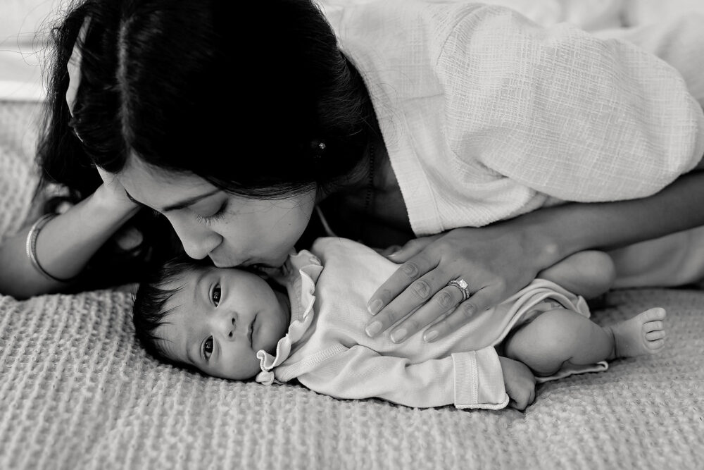 Black and white image of mom kissing newborn in Rhode Island