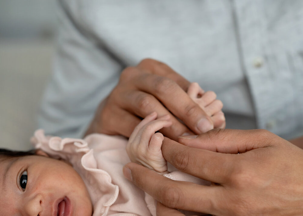 Close up of dad holding newborn's hand in Lincoln Rhode Island