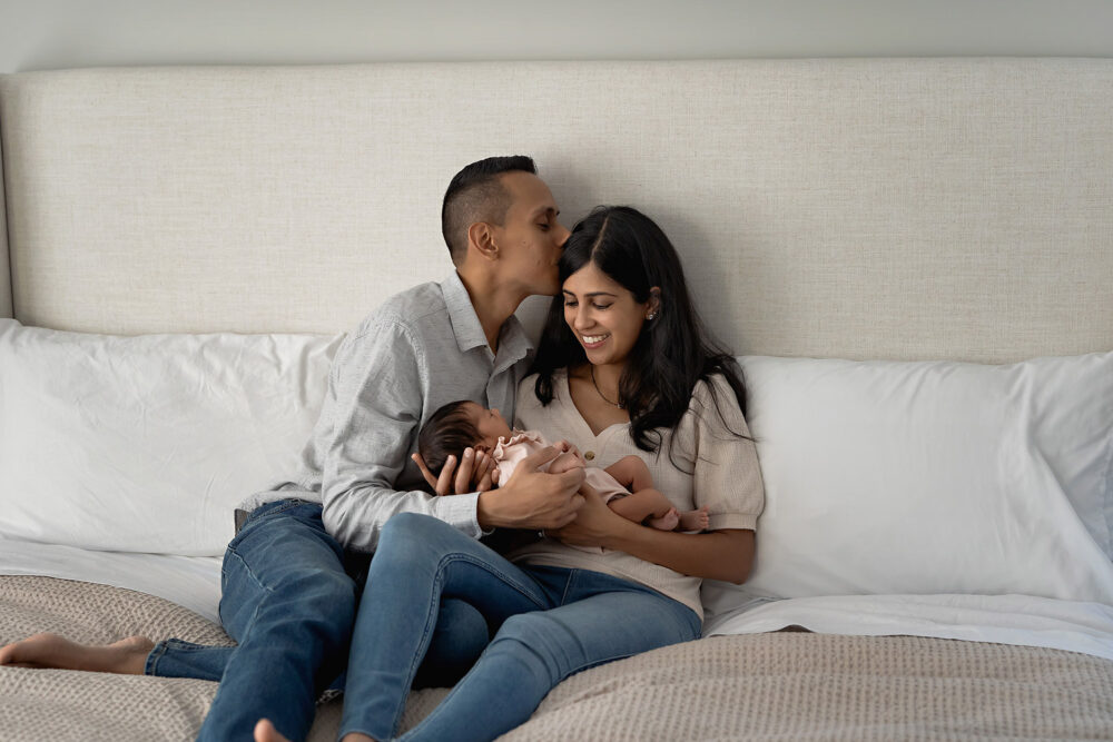 Dad kissing moms head during newborn photos in Rhode Island