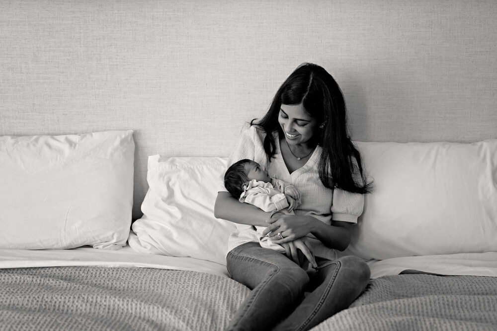 Mom and baby cuddling on bed in newborn photos in Barrington RI