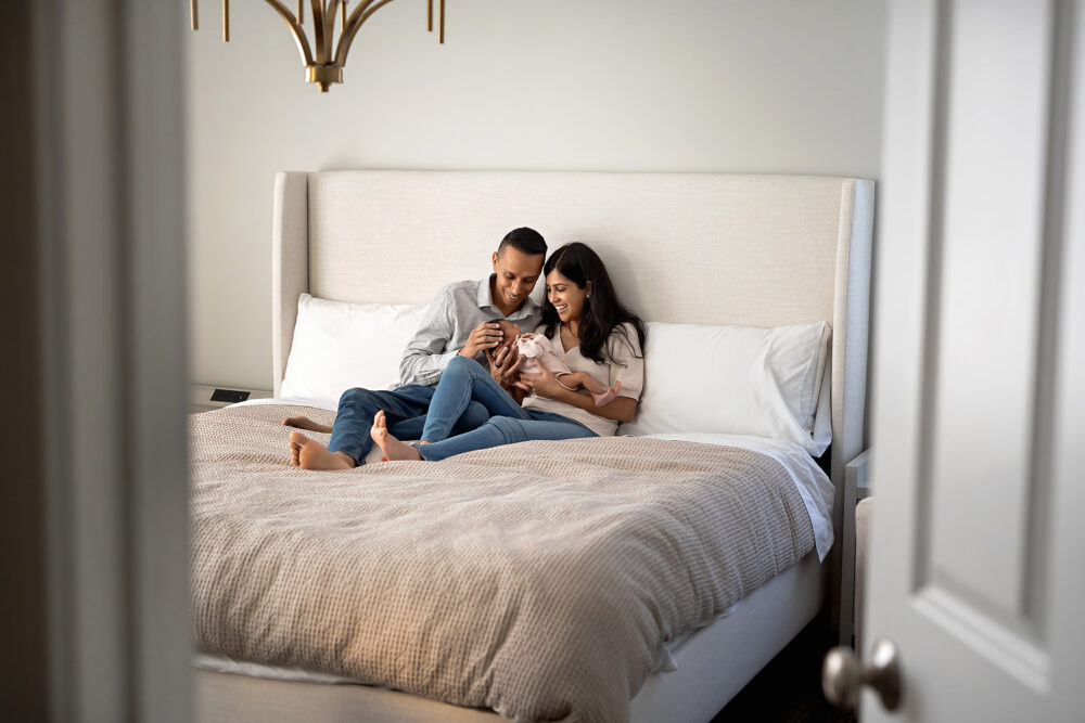 Mom and dad cuddling newborn on bed in Rhode Island