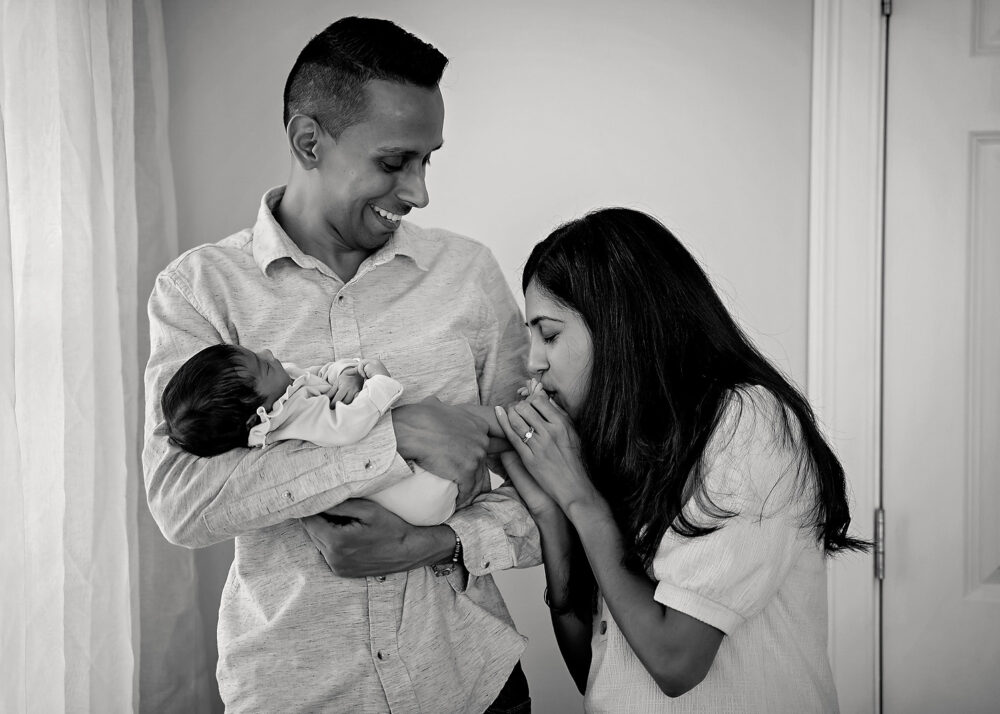 Mom kissing babys toes while dad holds her during newborn photos in Lincoln RI