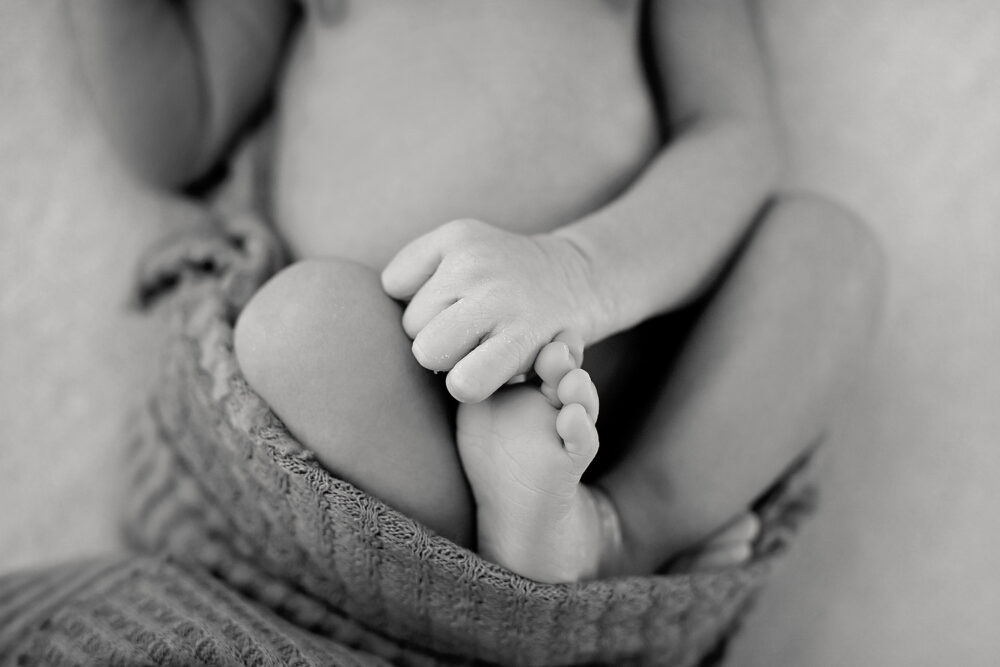 Newborn hand holding toes during photos in Rhode Island