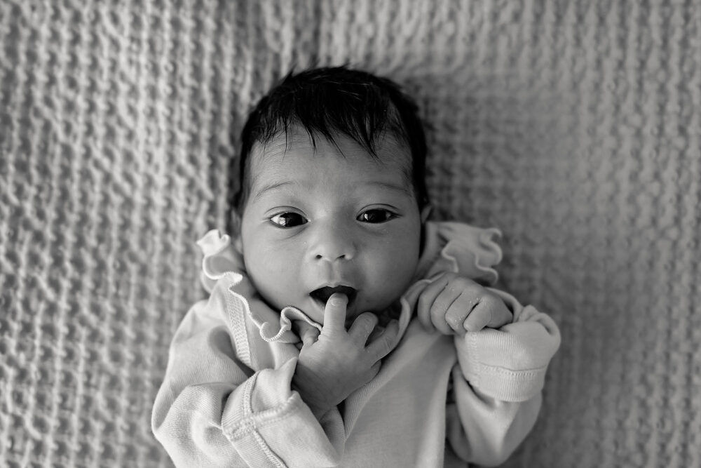 Overhead of baby on bed during in home newborn session in Newton Massachusetts