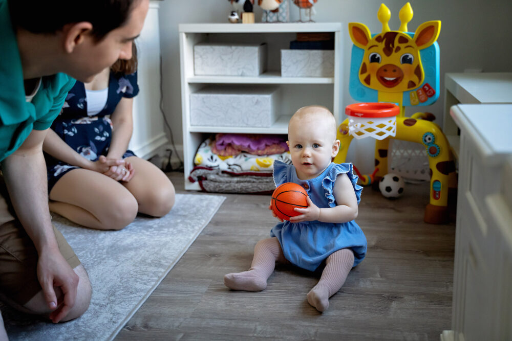 Baby playing ball with mom and dad toys near Providence RI