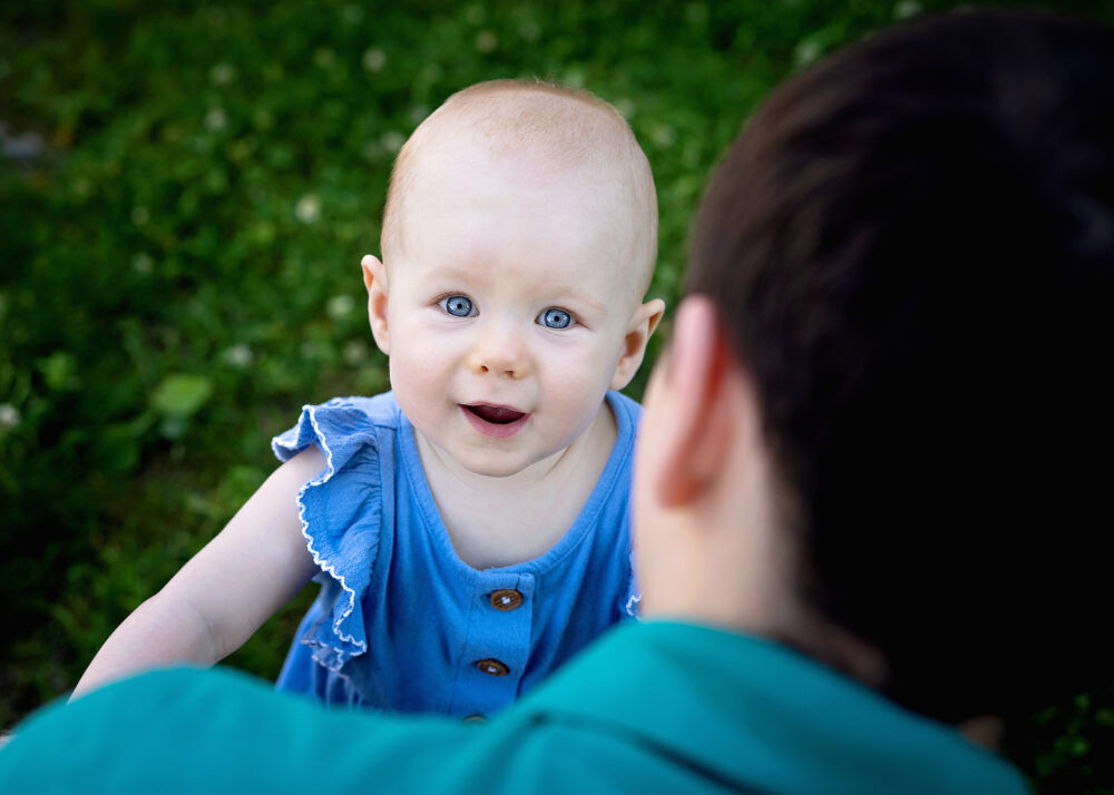 Blue eyed baby looking over dads shoulder near Providence RI