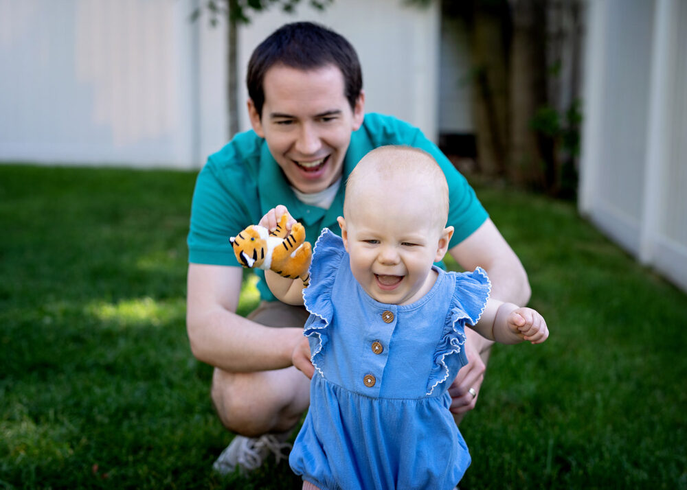 Walking baby with dad in background in family photos in Providence RI
