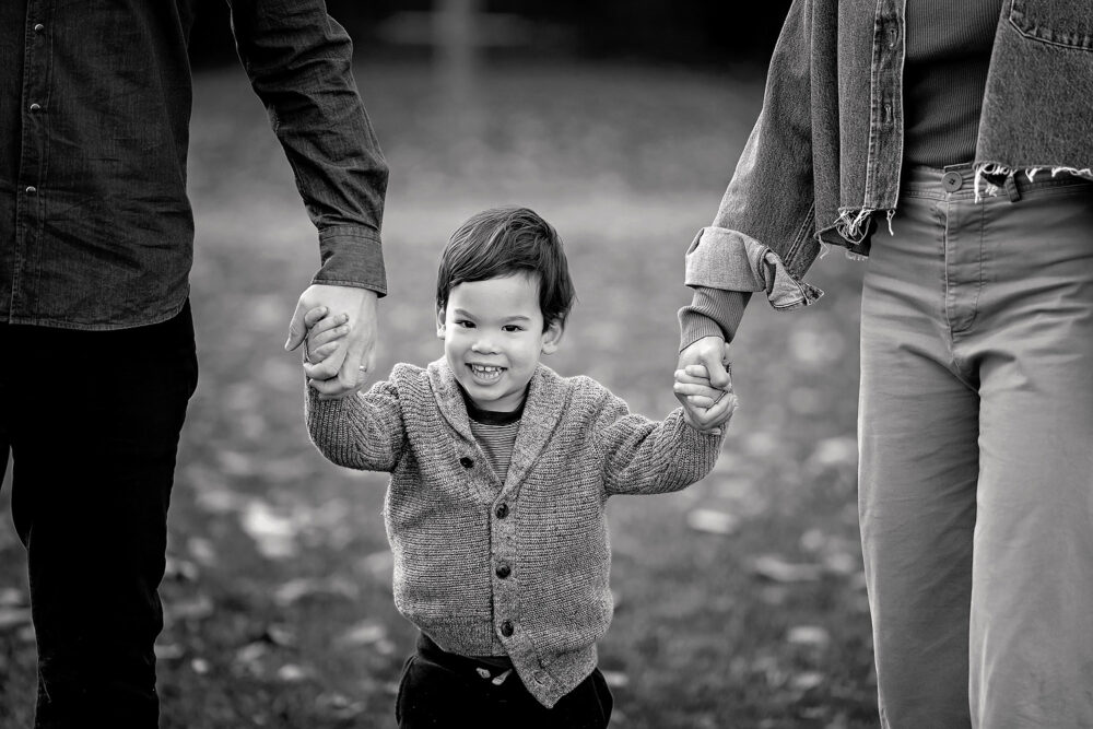 Young boy holding mom and dad's hands in family session East Side of Priovidence RI