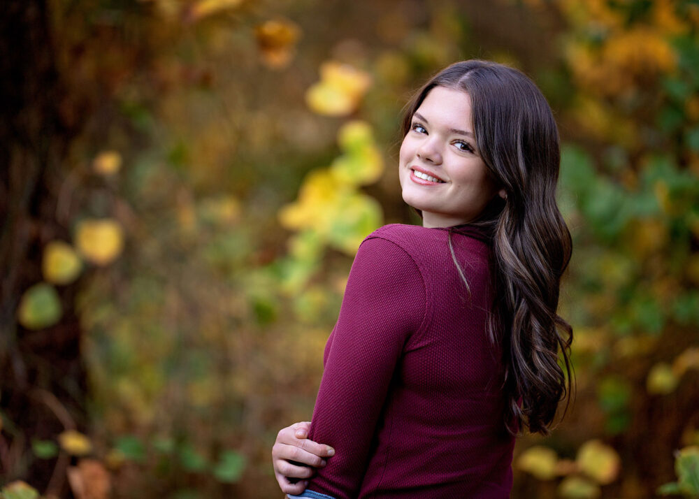 Senior girl looking over her shoulder during fall photos in Lincoln Rhode Island
