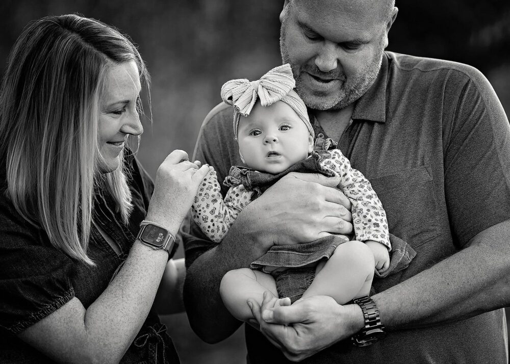 Mom and dad holding baby girl during family portraits in the fall in Rhode Island