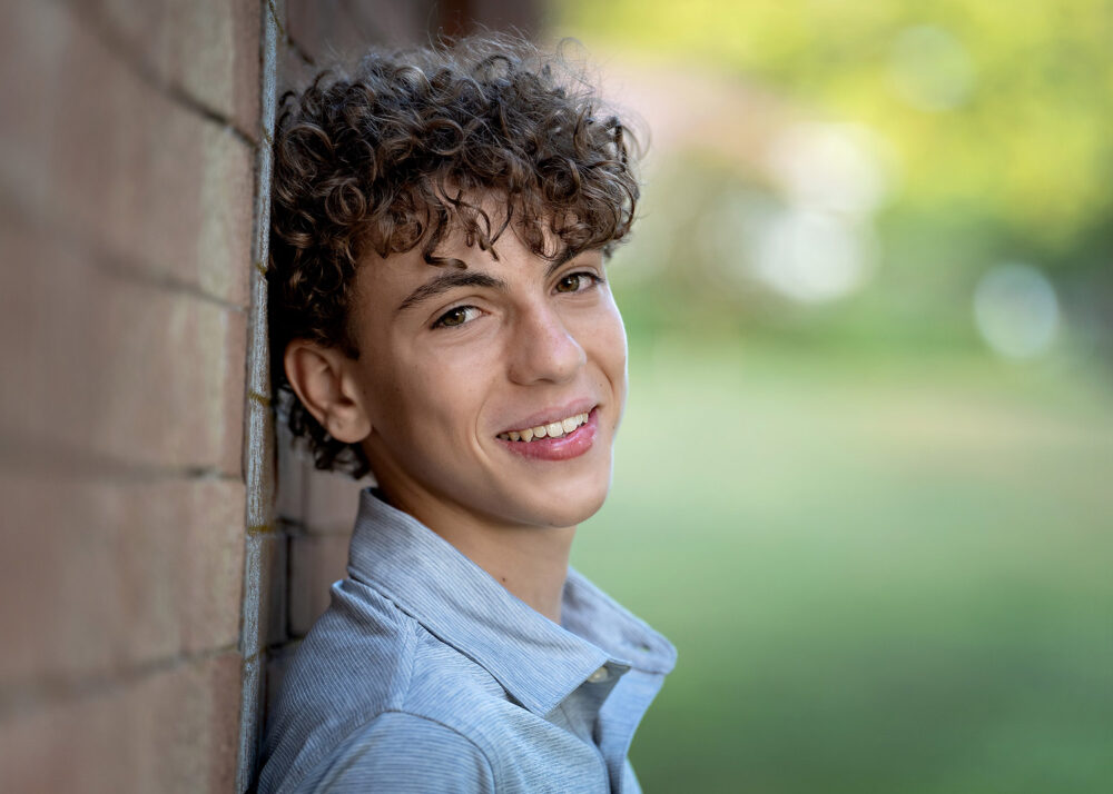 Senior boy against brick wall during senior photos in Waterford Connecticut