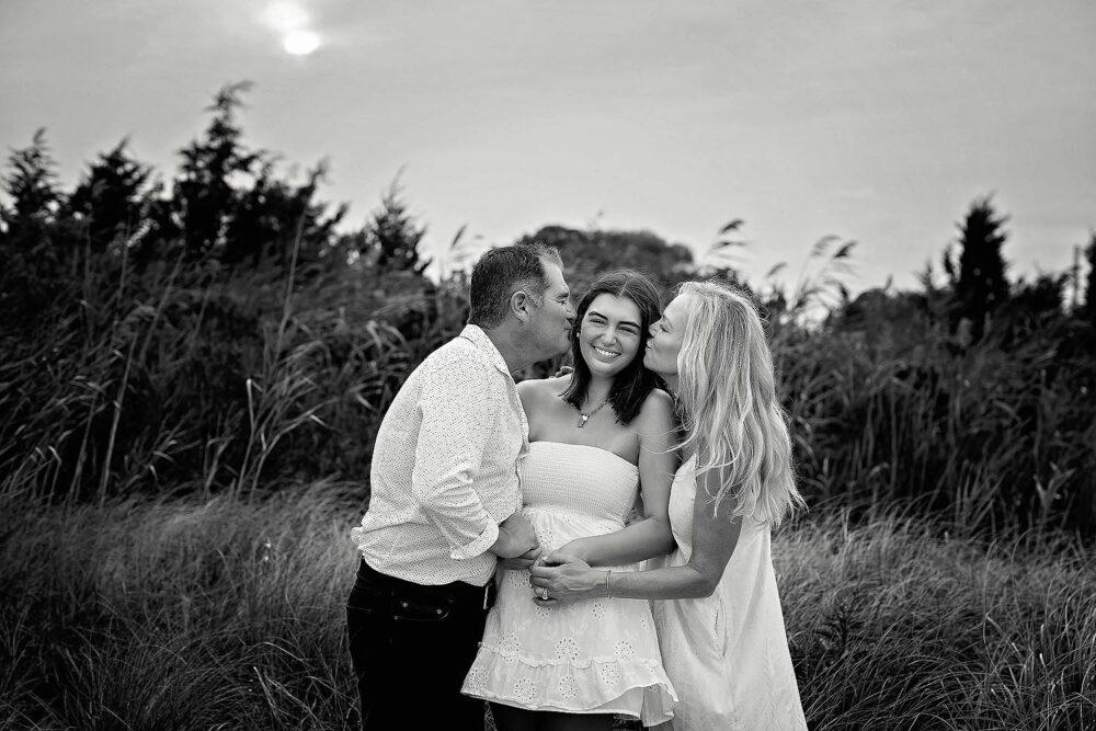 Mom and dad giving senior daughter a kiss during family photos in East Greenwich Rhode Island