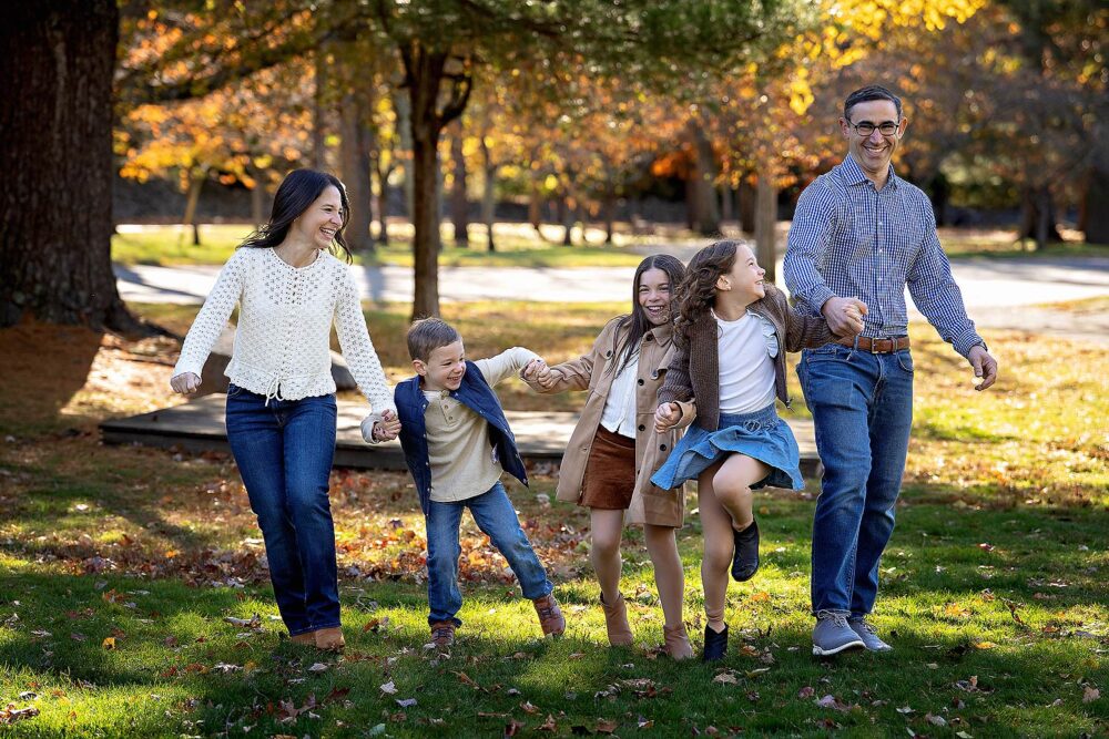 Family holding hands laughing during family portraits Blackstone Boulevard